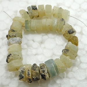 May include: A strand of light green and white gemstone beads with a rough, natural finish. The beads are strung on a thin wire and are approximately 1 cm in diameter.