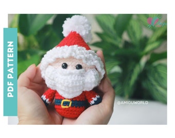 Puede incluir: Muñeco de Papá Noel tejido a ganchillo con gorro y traje rojos, barba blanca y ojos negros. El muñeco tiene un pompón blanco en el gorro y un cinturón negro. El texto "PDF PATTERN" está en el lado izquierdo de la imagen.