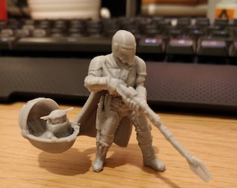 May include: A grey 3D printed figurine of a Mandalorian warrior holding a weapon and carrying a small grey creature in a pod.