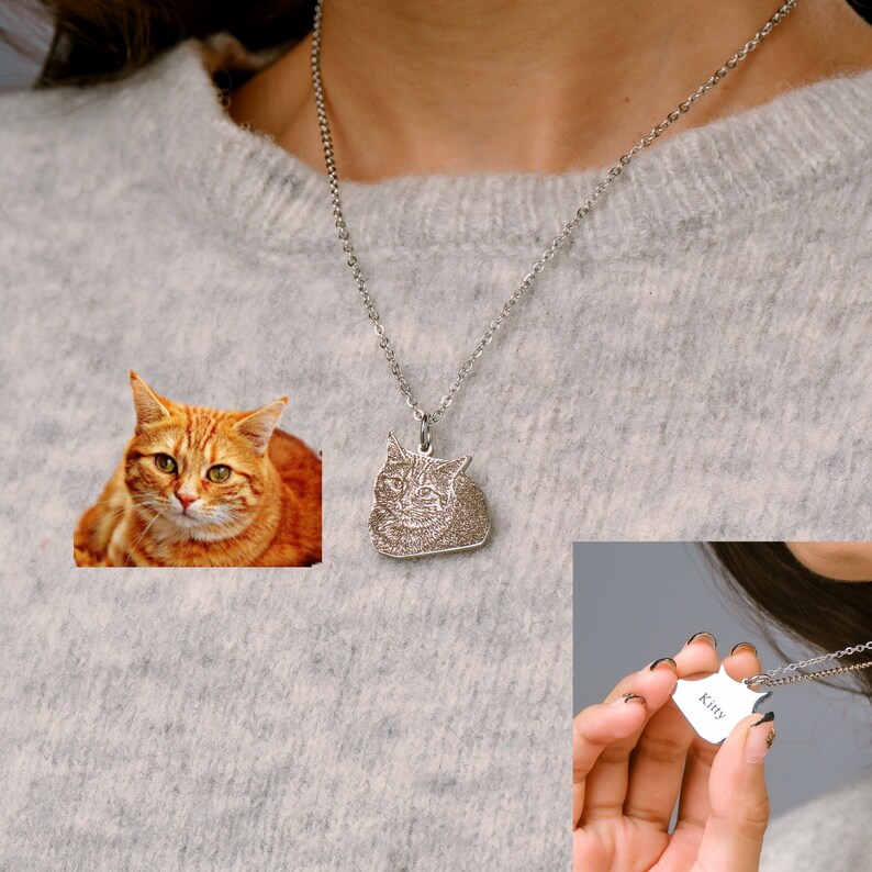 May include: A silver necklace with a pendant featuring a photo of a cat. The pendant is shaped like the cat's head. The necklace also has a smaller heart-shaped tag with the word "Kitty" engraved on it.