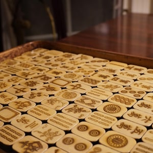Handcrafted wooden Mahjong tiles with engraved Riichi symbols arranged neatly on a tabletop.