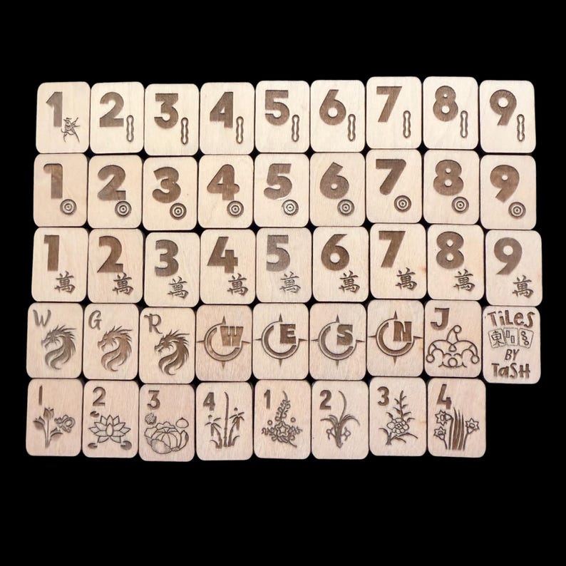 May include: A set of wooden tiles, each engraved with numbers, symbols, and illustrations. The tiles display numbers 1-9, Chinese characters, and various images. The text "Tiles by Tash" is also visible.