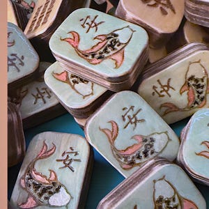 Finished Koi Fish Riichi Mahjong tiles handcrafted from layered wood and engraved using an xTool laser engraver.