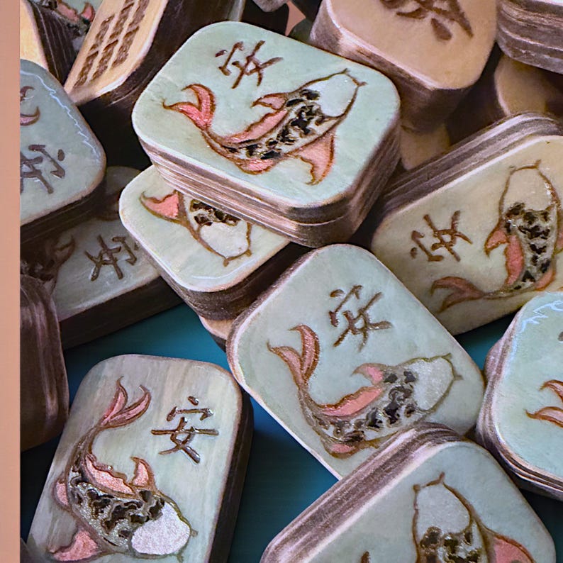 Finished Koi Fish Riichi Mahjong tiles handcrafted from layered wood and engraved using an xTool laser engraver.