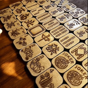 Handcrafted wooden American Mahjong tiles with engraved suits, flowers, and jokers on a wooden table.