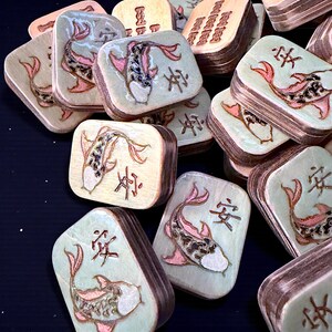 Finished Koi Fish Riichi Mahjong tiles handcrafted from layered wood and engraved using an xTool laser engraver.