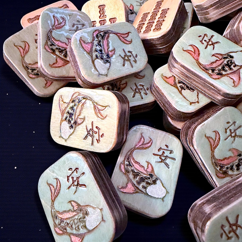 Finished Koi Fish Riichi Mahjong tiles handcrafted from layered wood and engraved using an xTool laser engraver.
