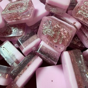 Pu&ograve; includere: Una collezione di blocchi di resina rosa e trasparente con glitter incorporati e caratteri giapponesi. Alcuni blocchi hanno un design a strati con accenti glitterati. I blocchi sono di varie forme e dimensioni.