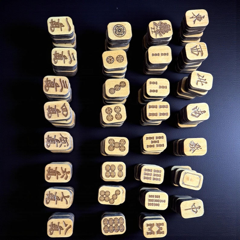 May include: A collection of wooden Mahjong tiles, each with unique symbols and characters. The tiles are stacked in small piles, showcasing the variety of designs and the game's traditional aesthetic. The natural wood color contrasts with the dark background.