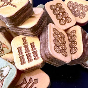 Finished Koi Fish Riichi Mahjong tiles handcrafted from layered wood and engraved using an xTool laser engraver.