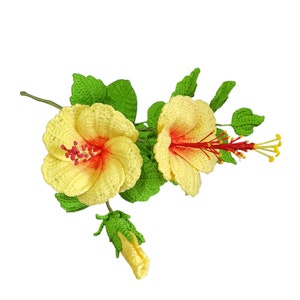 May include: A crocheted bouquet of yellow hibiscus flowers with red centres and green leaves. The flowers are arranged in a cluster with a bud at the bottom.
