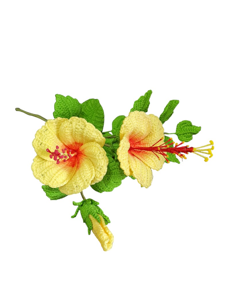 May include: A crocheted bouquet of yellow hibiscus flowers with red centres and green leaves. The flowers are arranged in a cluster with a bud at the bottom.