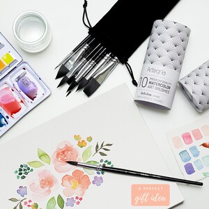 Op de afbeelding: Een set van 10 aquarelkwasten in een zwarte etui met een witte en grijze patroonbuis. De kwasten zijn gelabeld "Artegr&iacute;a Premium Quality Watercolor Art Brushes" en "Infodien Series Finest Synthetic Squirrel". De afbeelding toont ook een aquarelschilderij van bloemen, een aquarelpalet en een glas water.