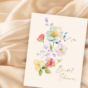 May include: A watercolor illustration of a floral bouquet with pink, yellow, blue, and white flowers. The text "Bridal Shower" is written in gold script at the bottom of the card.