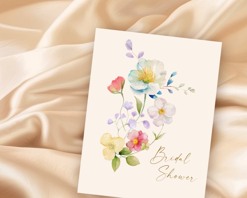 May include: A watercolor illustration of a floral bouquet with pink, yellow, blue, and white flowers. The text "Bridal Shower" is written in gold script at the bottom of the card.