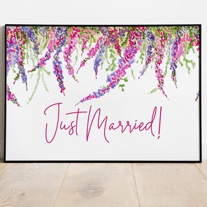 May include: A white framed print with a floral design in shades of purple, pink, and green. The text "Just Married!" is written in pink cursive.
