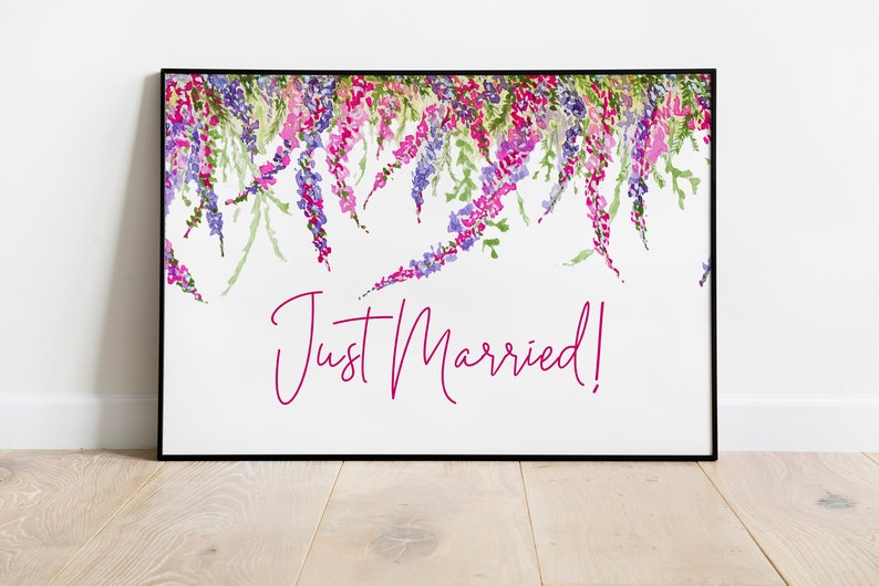 May include: A white framed print with a floral design in shades of purple, pink, and green. The text "Just Married!" is written in pink cursive.