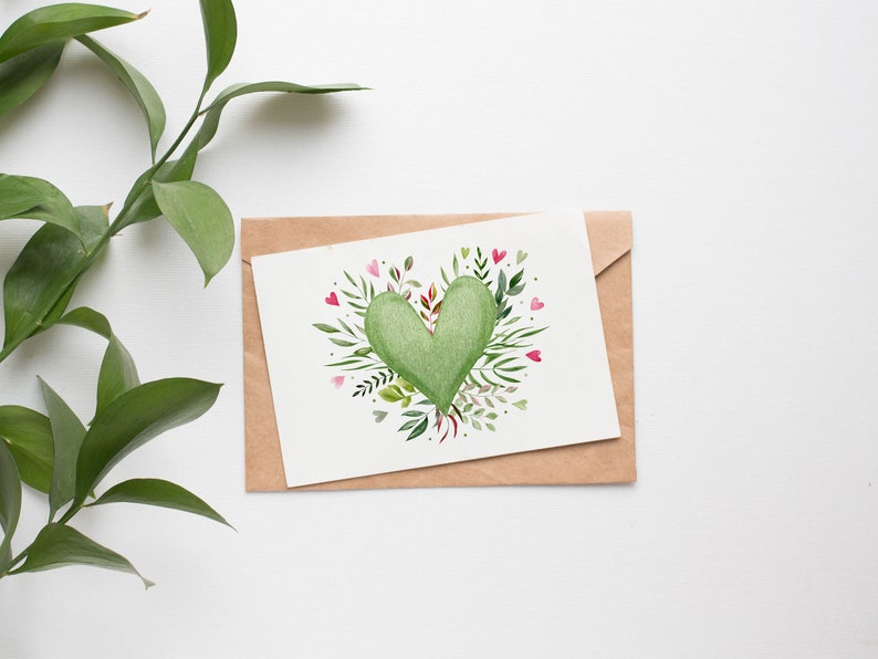 May include: A brown envelope with a white card inside. The card features a green heart surrounded by green leaves and pink flowers.