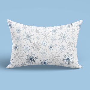May include: A white pillow with a blue and gray snowflake pattern. The pillow is soft and comfortable, perfect for adding a touch of winter cheer to your home.