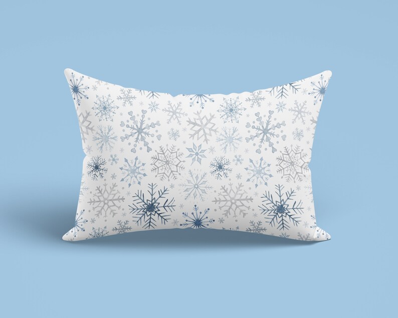 May include: A white pillow with a blue and gray snowflake pattern. The pillow is soft and comfortable, perfect for adding a touch of winter cheer to your home.