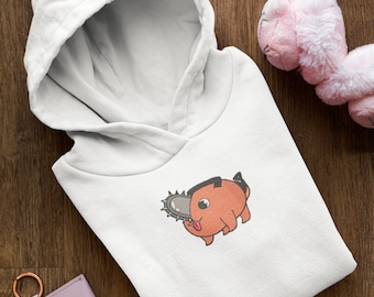 May include: White hooded sweatshirt with a cartoon illustration of a pink creature holding a chainsaw. The creature has a black eye and a pink tongue sticking out.