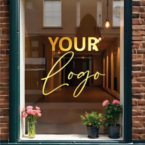 Könnte beinhalten: Ein Schaufenster mit dem goldenen Schriftzug "YOUR Logo". Der Fensterrahmen ist dunkelgrün, mit einer weißen Fensterbank, auf der sich eine Vase mit rosa Blumen und Topfpflanzen befinden. Das Gebäude hat eine Backsteinfassade.