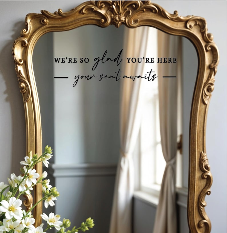 May include: A gold-framed mirror with a black vinyl decal that reads "We're so glad you're here - your seat awaits - "