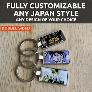 Puede incluir: Llaveros personalizables con diseños de matrículas japonesas. Los llaveros presentan varios diseños, incluyendo el texto "JAPAN 1" y "SAKURA". Los llaveros son de doble cara y tienen anillos plateados. El texto "FULLY CUSTOMIZABLE" está en la parte superior.