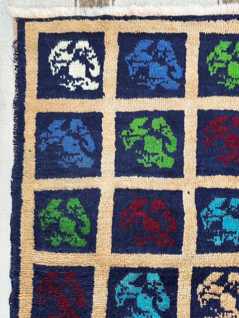 May include: A close-up of a blue rug with a repeating pattern of stylized trees in various colors, including white, blue, green, and red.