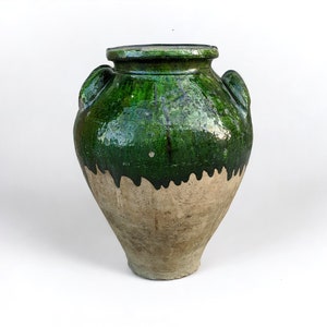 May include: A large green glazed ceramic jar with two handles on the sides. The jar has a brown unglazed base.
