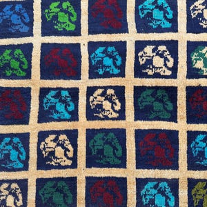 May include: A blue and beige rug with a repeating pattern of stylized trees in various colors, including green, red, and blue.