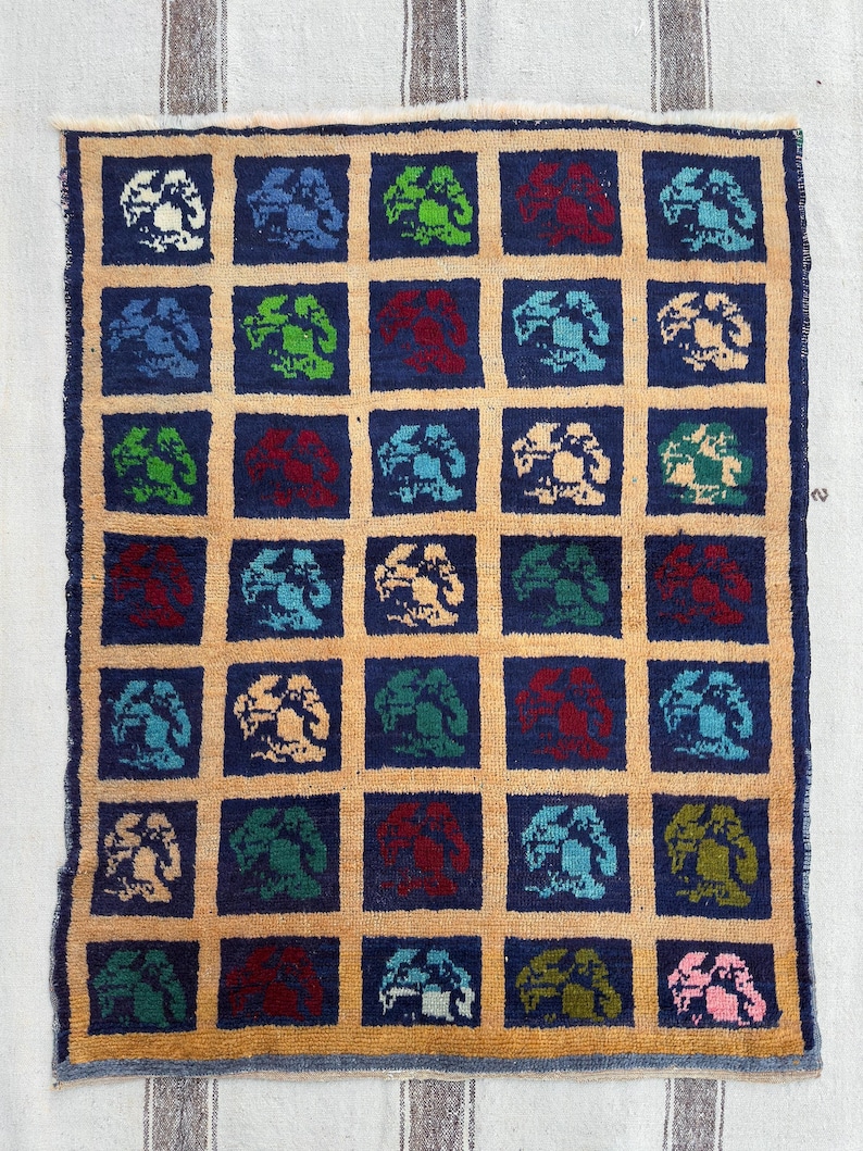 May include: A cream-colored rug with a repeating pattern of blue, green, red, and white stylized trees. The trees are arranged in a grid pattern on a dark blue background.