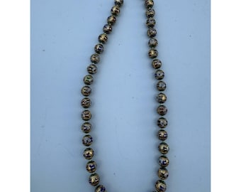 May include: A beaded necklace with gold-colored beads. Each bead has a detailed design with red, blue, and green accents. The necklace is strung on a thin, silver-colored chain.