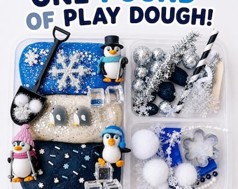 May include: A clear plastic container holding one pound of play dough in blue, white, and dark blue, accompanied by penguin figurines, silver snowflake ornaments, white pom-poms, clear plastic ice cubes, and a black plastic shovel.