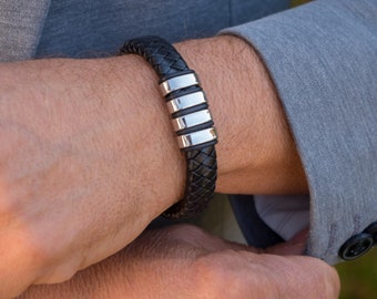 Peut inclure: Un bracelet en cuir noir avec un accent en métal argenté. Le bracelet est tressé et a une finition polie.