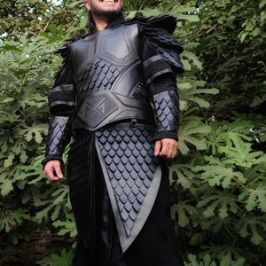 Puede incluir: Un traje de armadura de cuero negro con un patr&oacute;n de escamas y un cintur&oacute;n con hebilla. La armadura tiene un dise&ntilde;o decorativo en la pieza del pecho.