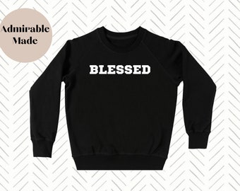 May include: Black sweatshirt with the word "BLESSED" printed in white on the front.