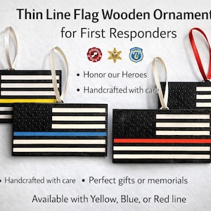 May include: Wooden ornaments in the shape of the American flag, featuring a black background with white stripes and a colored line. The ornaments are available with yellow, blue, or red lines, and are designed for first responders. Each ornament has a ribbon for hanging.