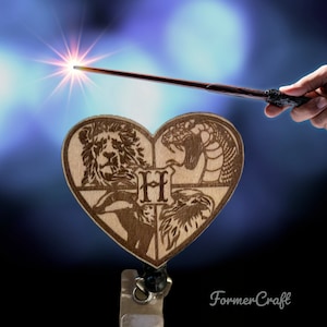 Può includere: Un ciondolo a forma di cuore in legno con gli stemmi delle case di Hogwarts, un leone, un serpente, un tasso e un'aquila, con la lettera "H" al centro. Il ciondolo è attaccato a un porta badge retrattile nero.