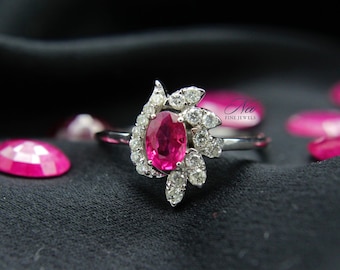May include: A silver ring featuring a pink oval gemstone surrounded by smaller white gemstones. The ring is set in a floral design.