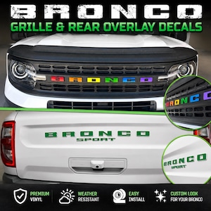 May include: White Bronco with a black grille and rear overlay decals. The grille features the word "BRONCO" in rainbow colors. The rear of the vehicle has the words "BRONCO SPORT" in green.