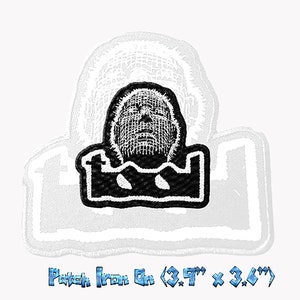 May include: Black and white embroidered patch with a stylized face design. The patch, measuring approximately 9.9 cm by 9.1 cm, is iron-on. The design has a textured appearance. The text at the bottom says 'Patch Iron On'.