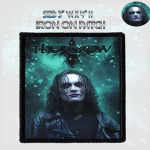 May include: Iron-on patch featuring a black and white image of The Crow, a comic book character, with the text "The Crow" above him. The background is a dark blue with a green tint and white specks.