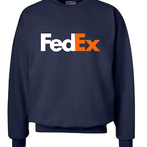 May include: Navy blue sweatshirt with the FedEx logo in white and orange. The word "Fed" is in white, and "Ex" is in orange. The sweatshirt has a crew neck and long sleeves with ribbed cuffs.