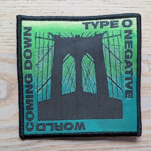 May include: Square patch with a black Brooklyn Bridge silhouette on a green and teal background. The words "TYPE O NEGATIVE", "COMING DOWN", and "WORLD" are printed around the bridge.