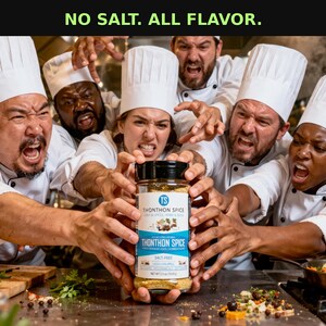 May include: A group of chefs in white uniforms and hats reaching for a jar of Thonthon Spice. The jar has a blue and white label with the text "Thonthon Spice" and "Salt Free." The image includes the text "NO SALT. ALL FLAVOR."