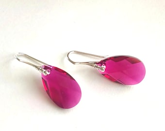 May include: A pair of silver dangle earrings with teardrop-shaped pink crystal stones.
