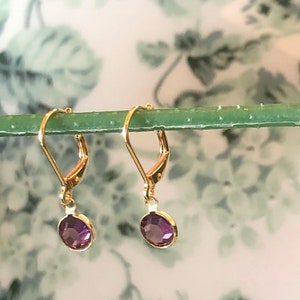 May include: A pair of gold dangle earrings with purple gemstone accents.