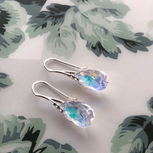 May include: A pair of silver teardrop earrings with iridescent crystal drops.