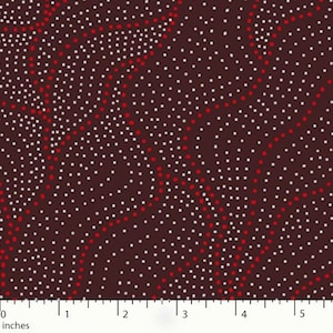 May include: Close-up of a fabric with a dark brown background. The fabric features a pattern of white and red dots arranged in diagonal lines and clusters. The dots vary in size, creating a textured appearance. The image includes an inch ruler along the bottom.